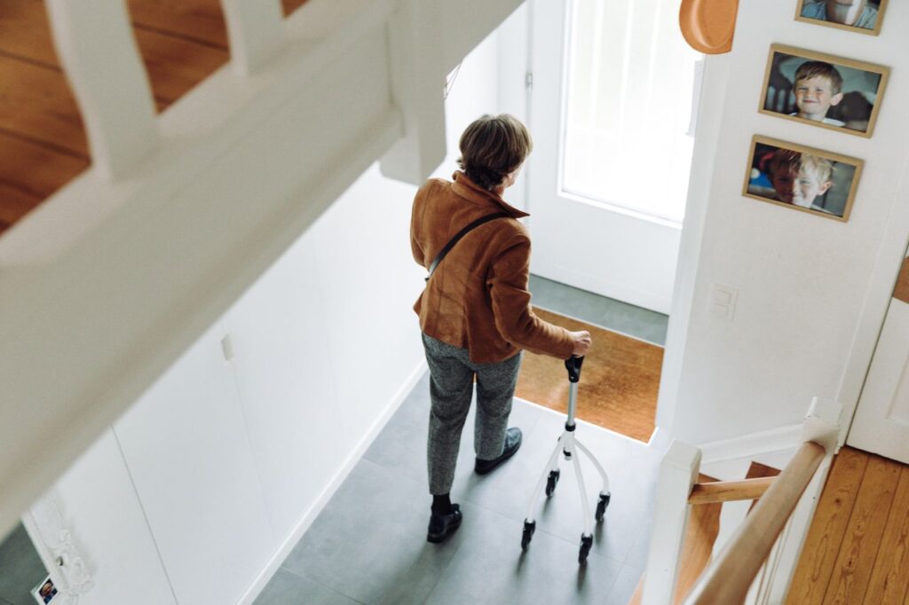 A senior adult walking indoors with a rollator, depicting independence and mobility.